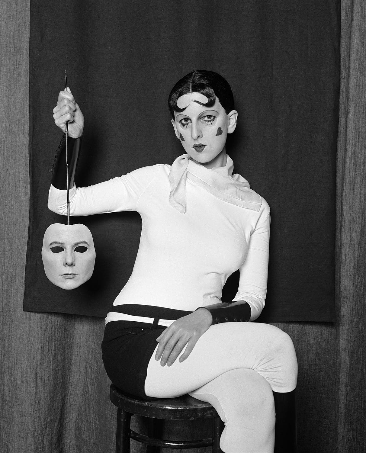 Black and white image of a young woman holding a mask